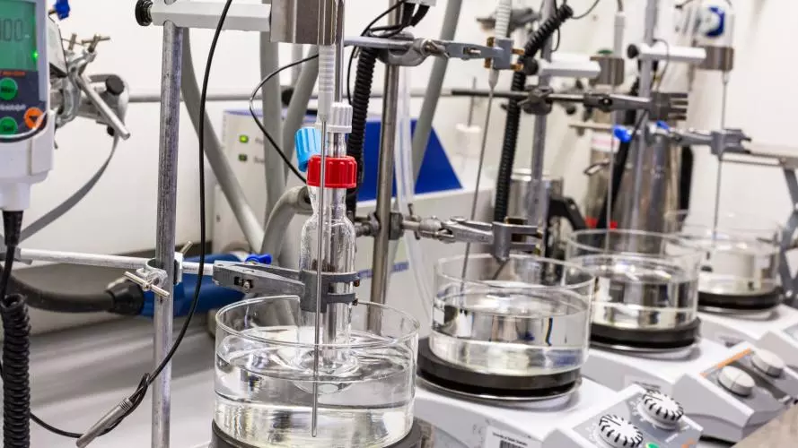 A series of oil baths and hotplate stirrers, a reaction flask is seated in the closest one