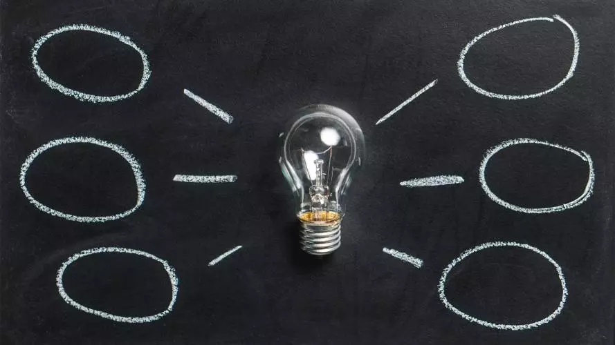 Lightbulb on a black background with thought/idea bubbles around it