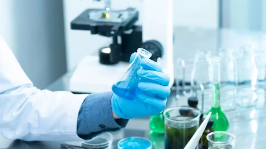 A chemist holding a flask containing a blue substance