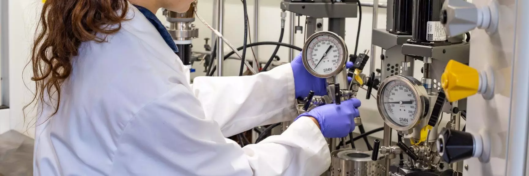 A scientist in a white lab coat assembling a polymerization reactor