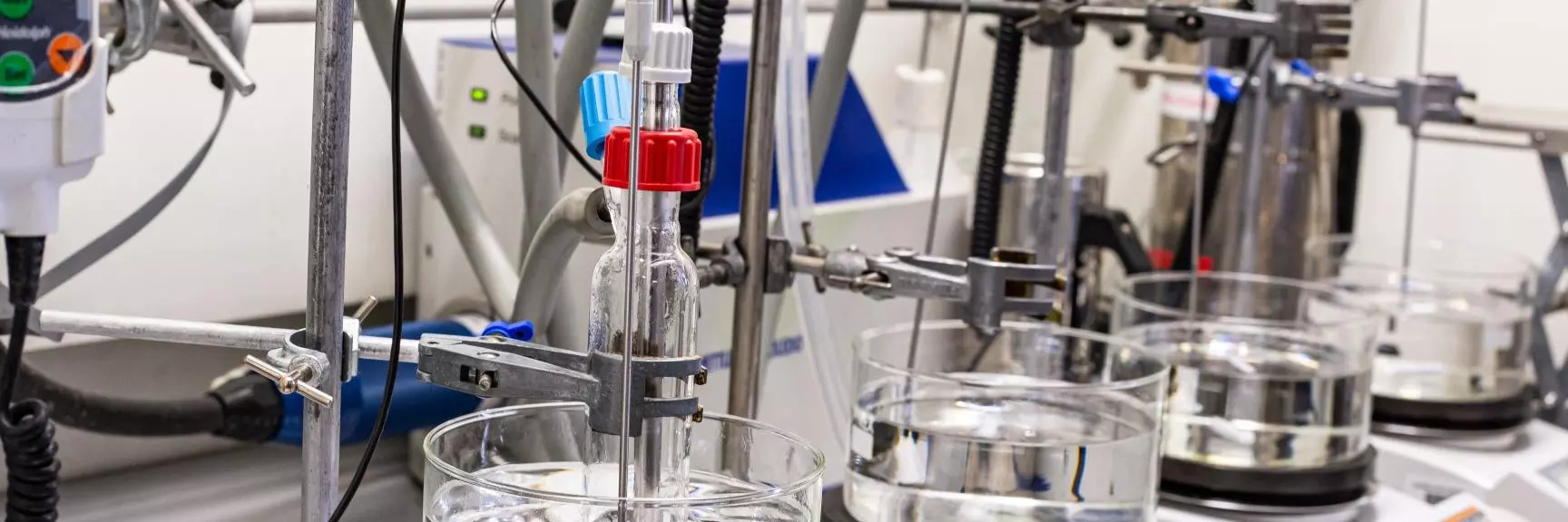 A series of oil baths and hotplate stirrers, a reaction flask is seated in the closest one