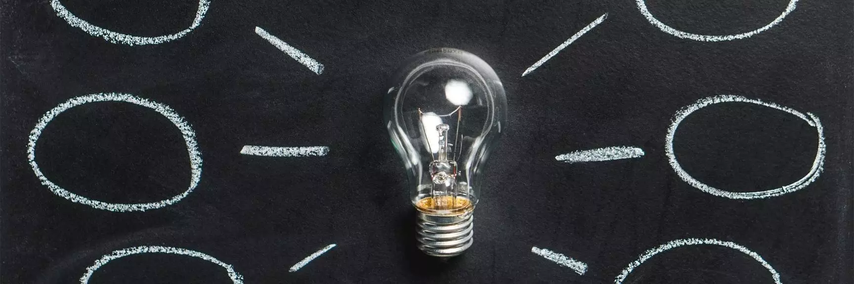 Lightbulb on a black background with thought/idea bubbles around it