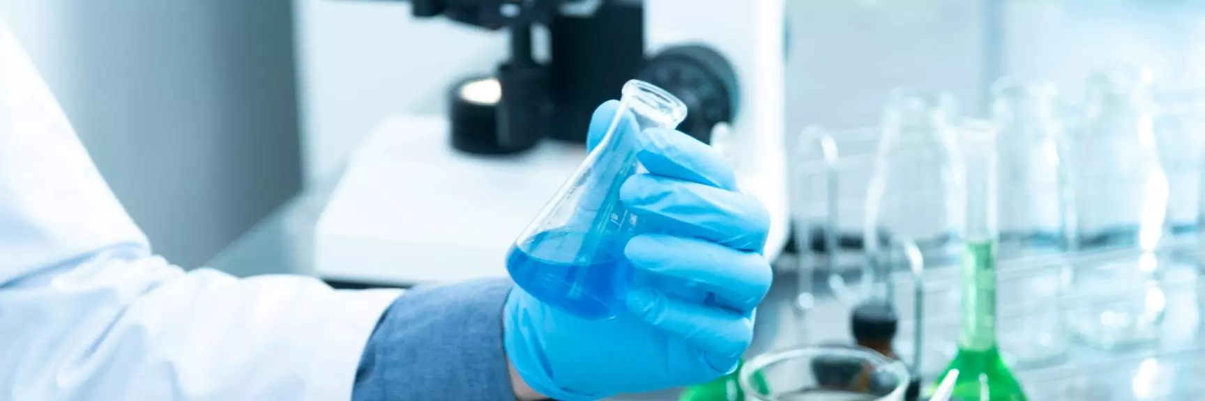 A chemist holding a flask containing a blue substance