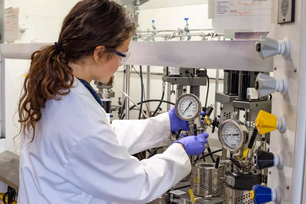 A scientist in a white lab coat assembling a polymerization reactor