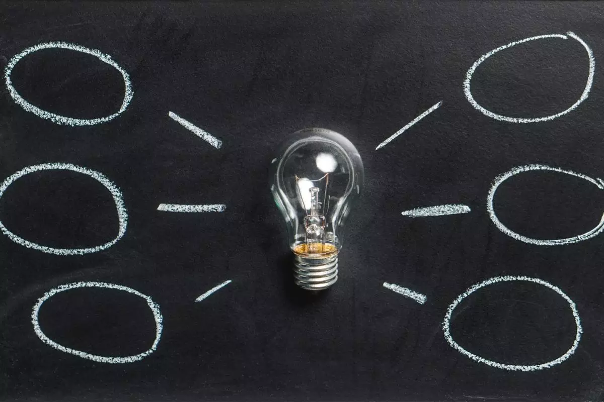 Lightbulb on a black background with thought/idea bubbles around it